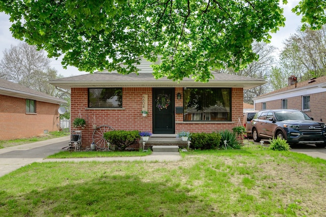 bungalow-style house with brick siding and a front yard