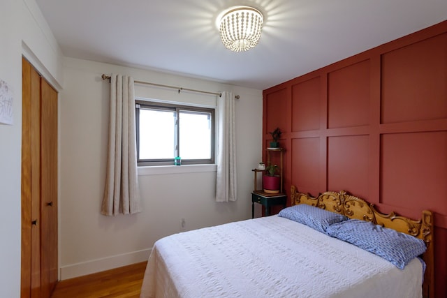 bedroom featuring baseboards, a notable chandelier, and light wood-style floors