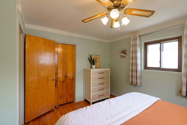 bedroom with a closet, a ceiling fan, crown molding, and wood finished floors