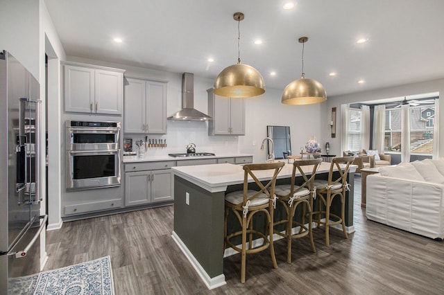 2670 Ironton Dr, Commerce Twp, MI 48382 - kitchen with wall chimney exhaust hood, stainless steel appliances, light countertops, dark wood-style floors, and open floor plan