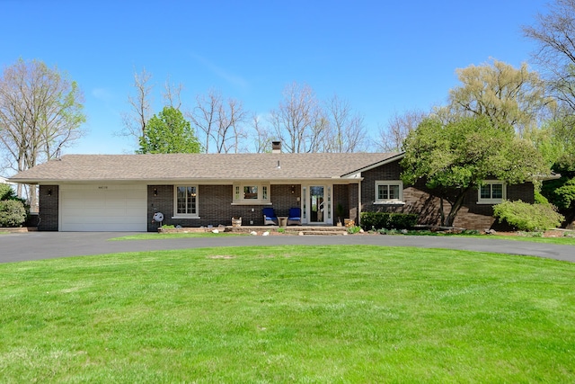 ranch-style house featuring a garage, driveway, brick siding, and a front yard