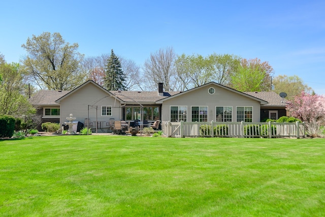 rear view of house featuring a yard, roof with shingles, a chimney, and a patio area