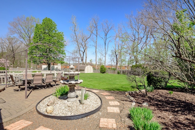 view of patio / terrace featuring a fenced backyard, an outbuilding, a storage shed, and outdoor dining space