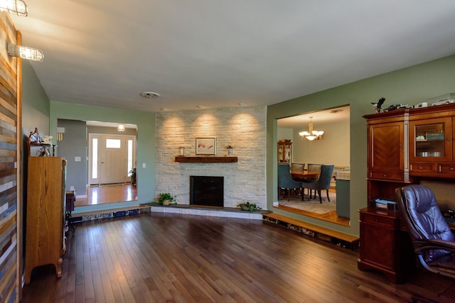 living room with a fireplace, a notable chandelier, and hardwood / wood-style flooring