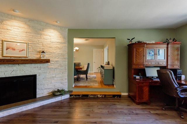 office with baseboards, wood finished floors, a chandelier, and a fireplace