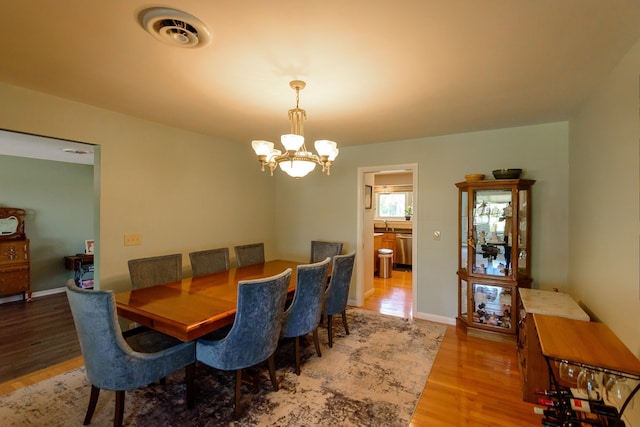 dining area featuring visible vents, wood finished floors, and a chandelier
