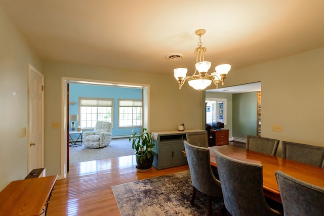 dining area featuring baseboard heating, a chandelier, wood finished floors, and visible vents