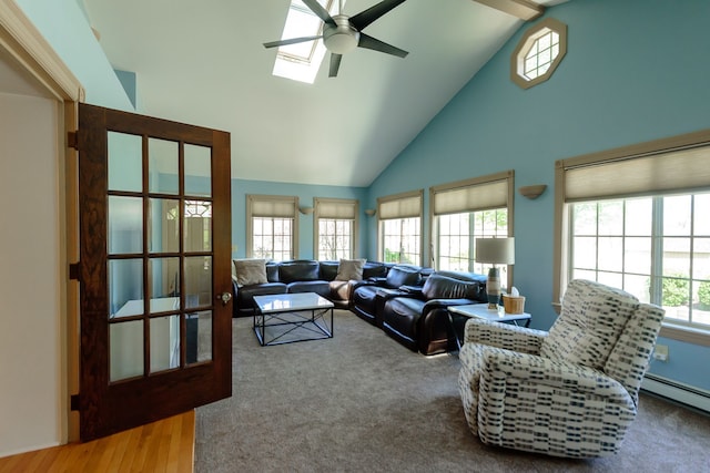 living area featuring a ceiling fan, high vaulted ceiling, a baseboard heating unit, and a skylight