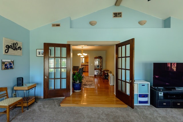 carpeted living area with visible vents, lofted ceiling, and french doors