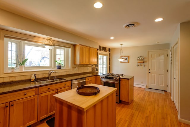 kitchen with a sink, butcher block countertops, stainless steel appliances, recessed lighting, and a peninsula
