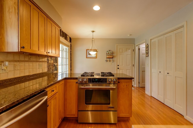 kitchen with brown cabinets, light wood-style flooring, stainless steel appliances, a peninsula, and backsplash