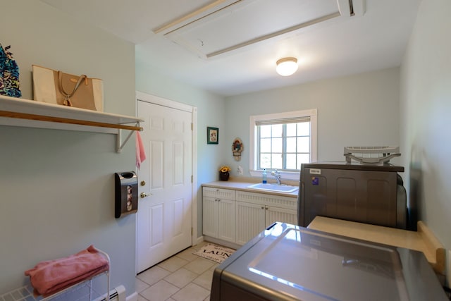 laundry area with attic access, washing machine and clothes dryer, a sink, cabinet space, and light tile patterned floors