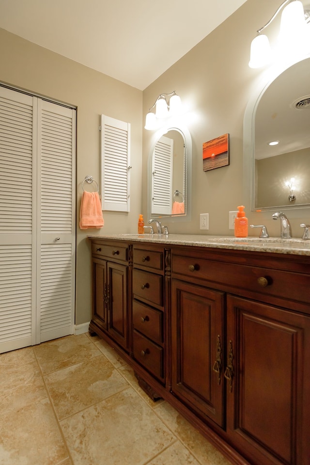 bathroom featuring visible vents, double vanity, a sink, and a closet