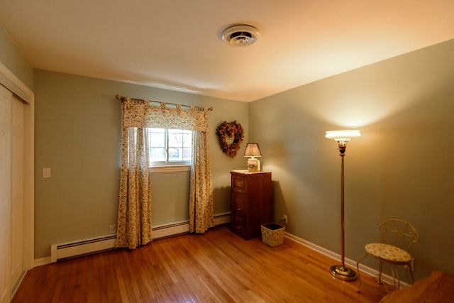 bedroom featuring visible vents, a baseboard radiator, baseboards, and hardwood / wood-style flooring