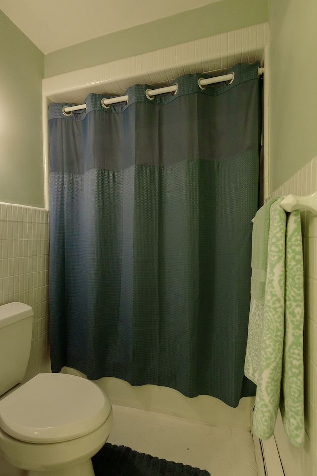 full bath with toilet, tile walls, curtained shower, and a wainscoted wall