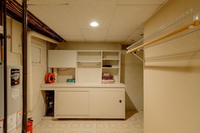 spacious closet featuring water heater, light floors, and a paneled ceiling