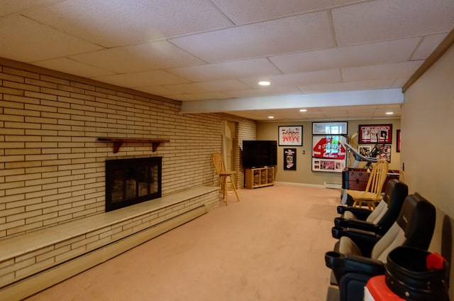 carpeted living area with a drop ceiling, a baseboard heating unit, and a fireplace