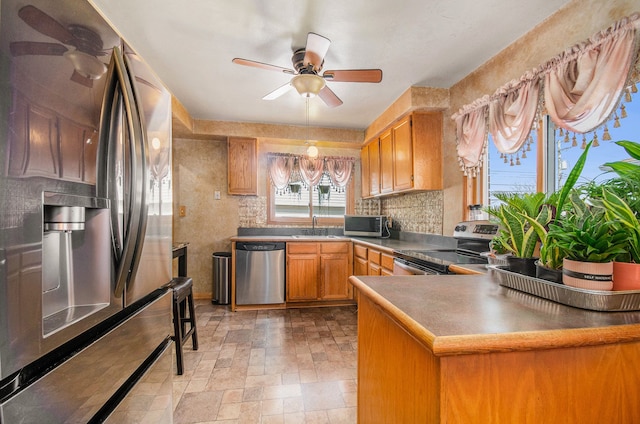 3440 Maidstone St, Trenton, MI 48183 - kitchen with stone finish floor, ceiling fan, appliances with stainless steel finishes, a sink, and a peninsula