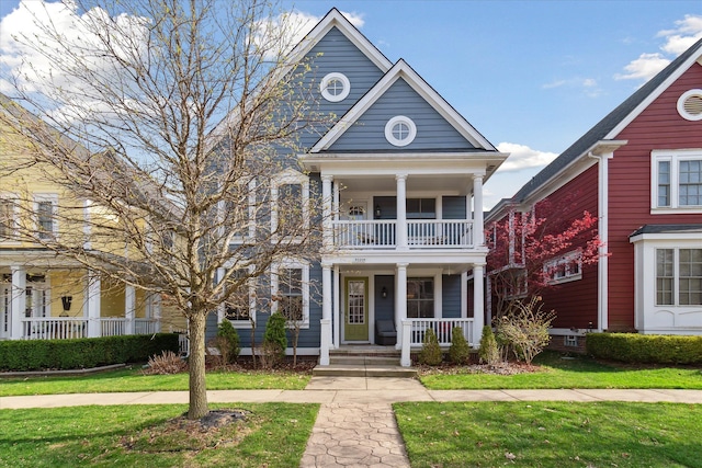 greek revival house with a front lawn, a balcony, and covered porch