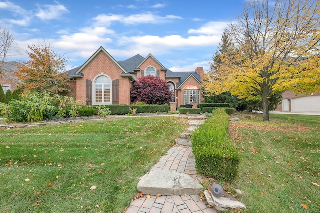 traditional home featuring a front yard, a chimney, and brick siding