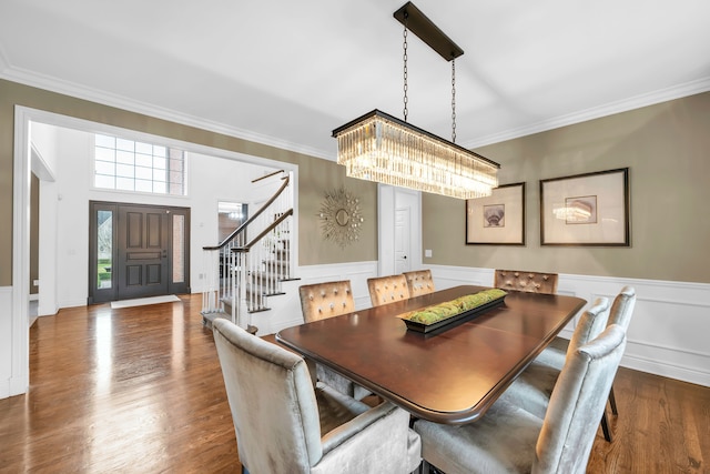 dining room with an inviting chandelier, stairway, crown molding, wainscoting, and wood finished floors