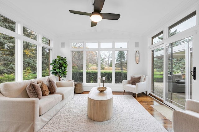 sunroom / solarium featuring wood finished floors, plenty of natural light, and vaulted ceiling with beams