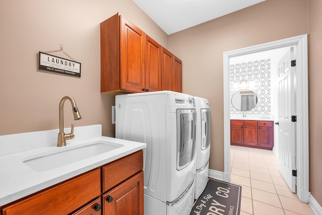 washroom featuring light tile patterned floors, cabinet space, washing machine and clothes dryer, a sink, and baseboards