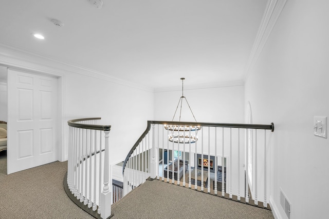 hallway featuring ornamental molding, a notable chandelier, an upstairs landing, and carpet floors