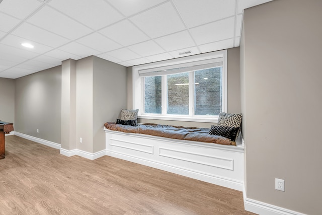 sitting room with wood finished floors, a drop ceiling, and baseboards