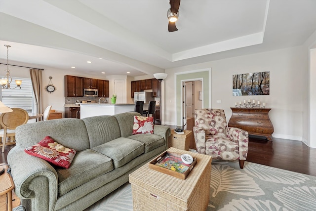 living room with arched walkways, ceiling fan with notable chandelier, recessed lighting, baseboards, and wood finished floors