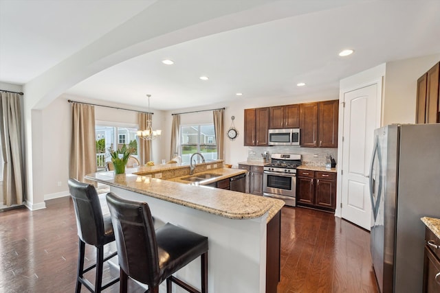 kitchen featuring dark wood-type flooring, a sink, appliances with stainless steel finishes, and arched walkways