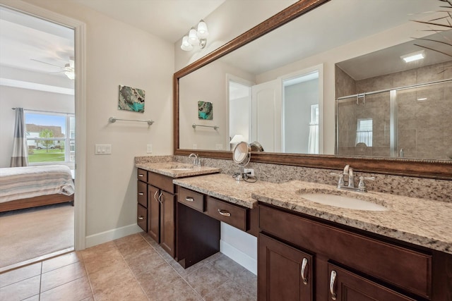 bathroom with double vanity, baseboards, a shower stall, and a sink