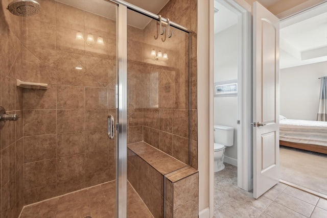 ensuite bathroom with toilet, tile patterned floors, ensuite bathroom, and a stall shower