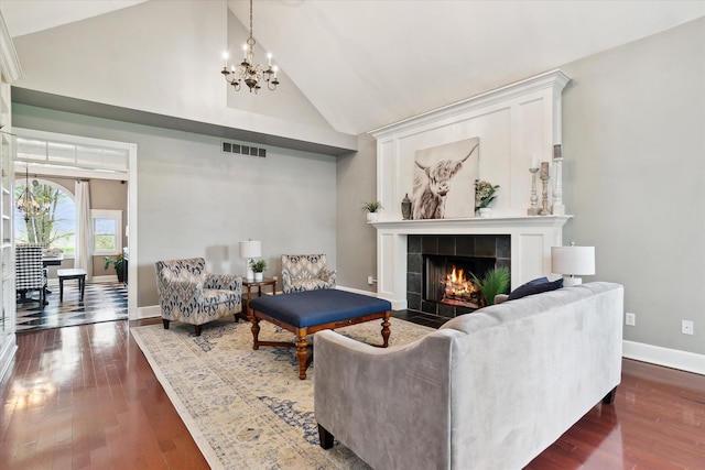 living area with a notable chandelier, high vaulted ceiling, baseboards, a tile fireplace, and visible vents