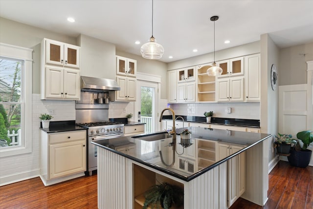 kitchen featuring open shelves, dark countertops, wall chimney range hood, a sink, and high end range