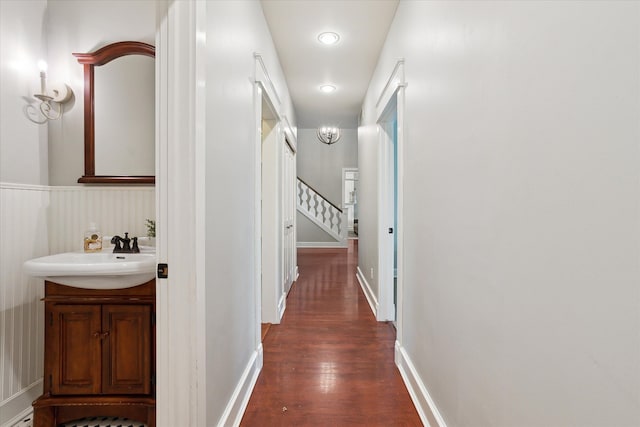 hallway featuring a sink, dark wood-style flooring, and stairs