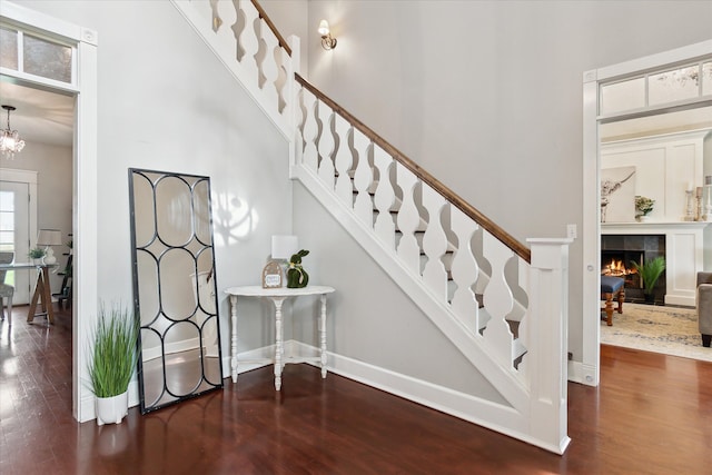 stairway with a high ceiling, wood finished floors, and a fireplace