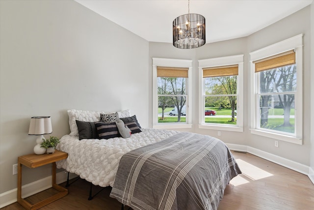 bedroom with an inviting chandelier, baseboards, and wood finished floors