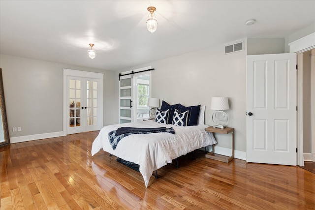 bedroom with baseboards, french doors, wood finished floors, and visible vents