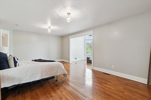 bedroom with baseboards, light wood finished floors, and visible vents