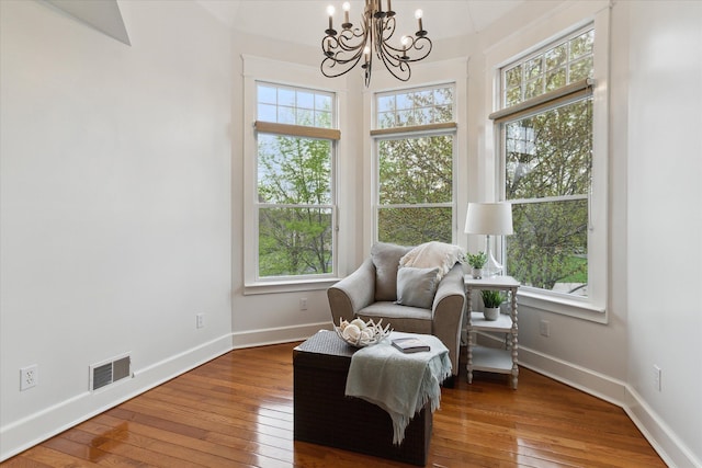living area featuring plenty of natural light, a notable chandelier, hardwood / wood-style floors, and visible vents