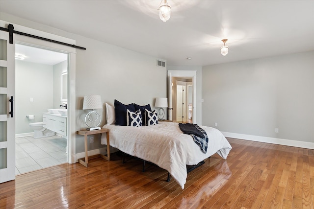 9730 Woodbend Dr, Saline, MI 48176 - bedroom with a barn door, baseboards, visible vents, and wood finished floors