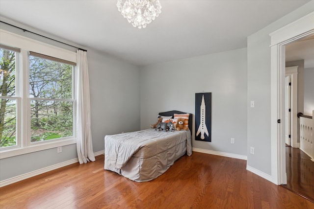 bedroom featuring baseboards, a chandelier, and wood finished floors