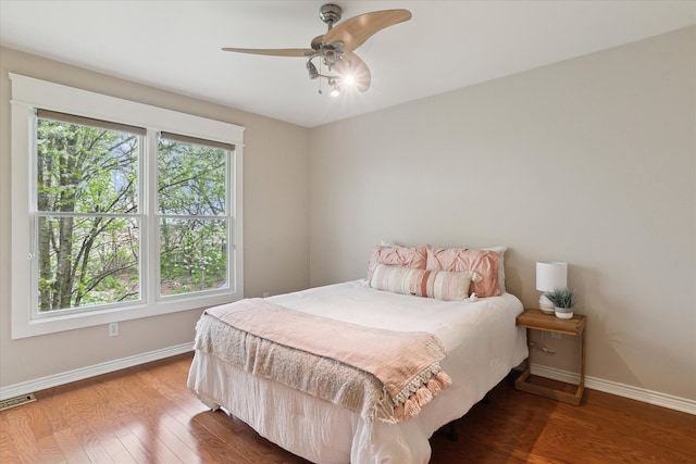 bedroom featuring baseboards, ceiling fan, wood finished floors, and visible vents