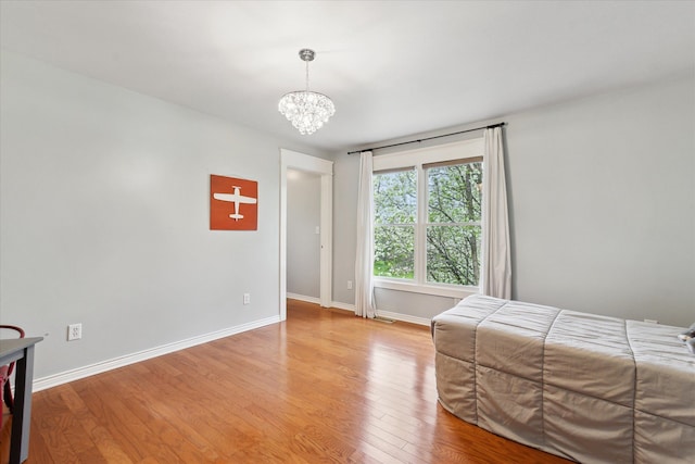 bedroom featuring an inviting chandelier, baseboards, and light wood-style floors