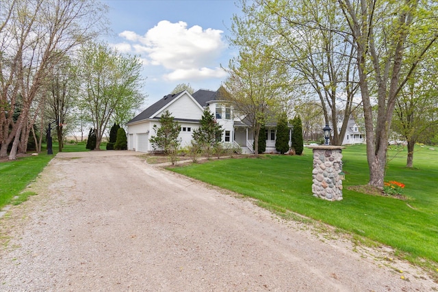 view of front of home featuring a garage, a front lawn, dirt driveway, and covered porch