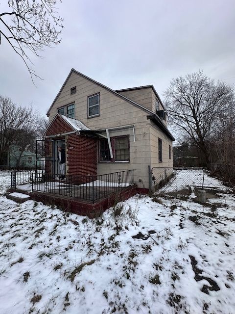 view of snowy exterior with a porch and fence