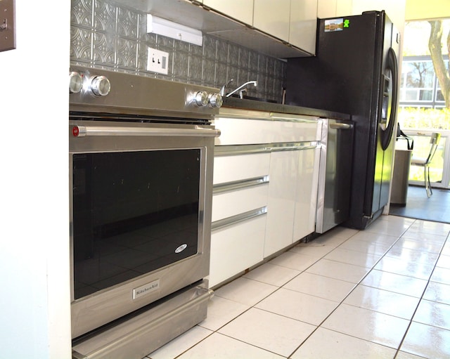 kitchen with stainless steel oven, white cabinetry, light tile patterned floors, tasteful backsplash, and black fridge with ice dispenser
