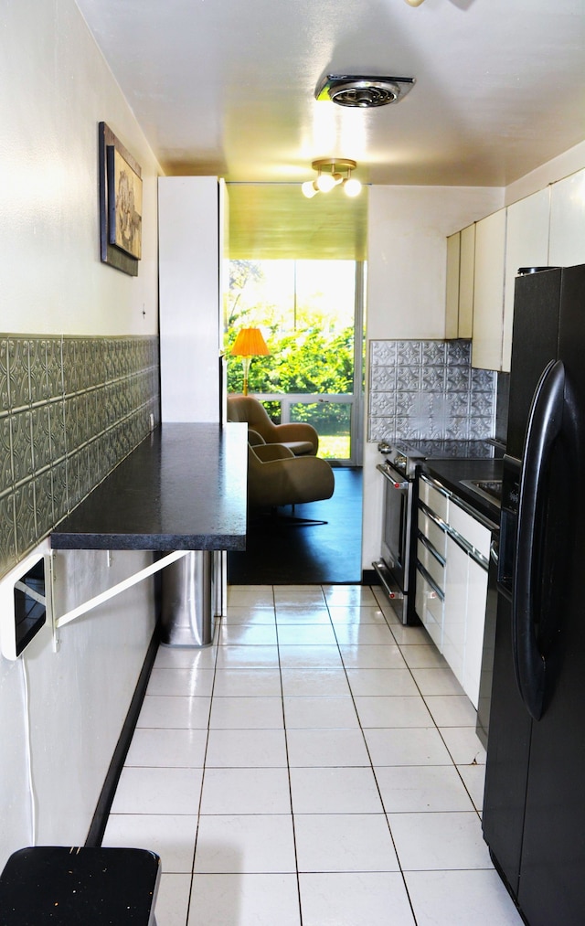 kitchen with decorative backsplash, black refrigerator with ice dispenser, dark countertops, white cabinetry, and light tile patterned floors