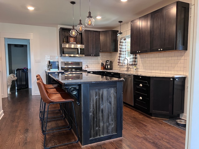 kitchen featuring light stone counters, a sink, backsplash, and stainless steel appliances